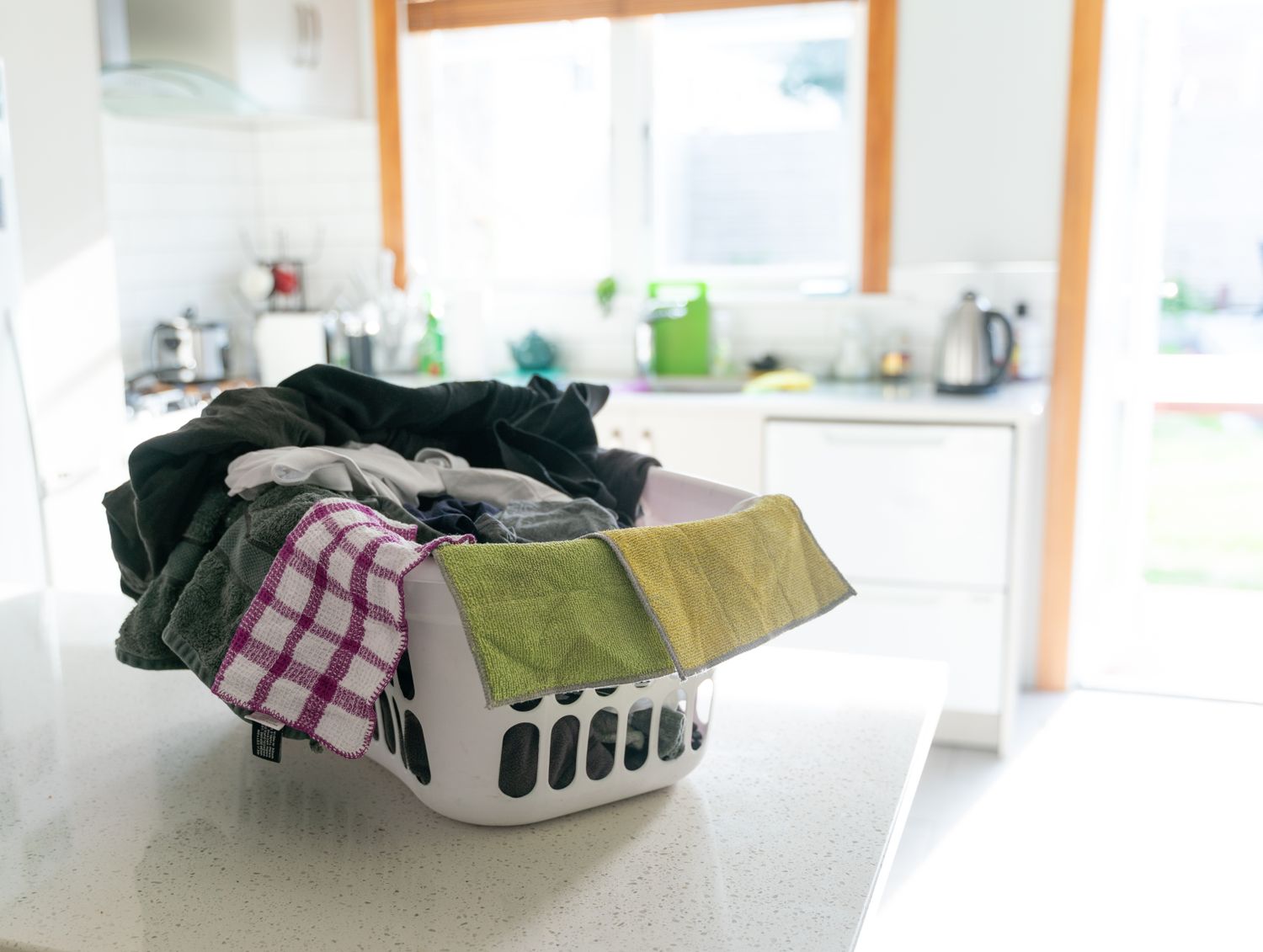 Laundry basket filled with assorted clothes on a kitchen counter
