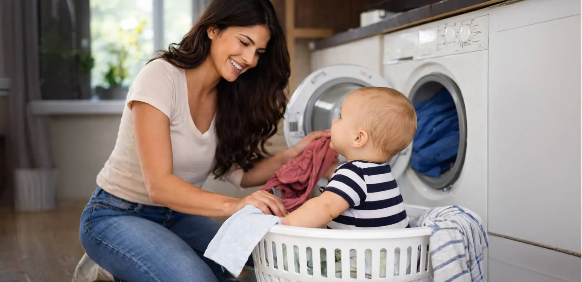 Woman and baby playing together in a laundry basket surrounded by colorful clothes