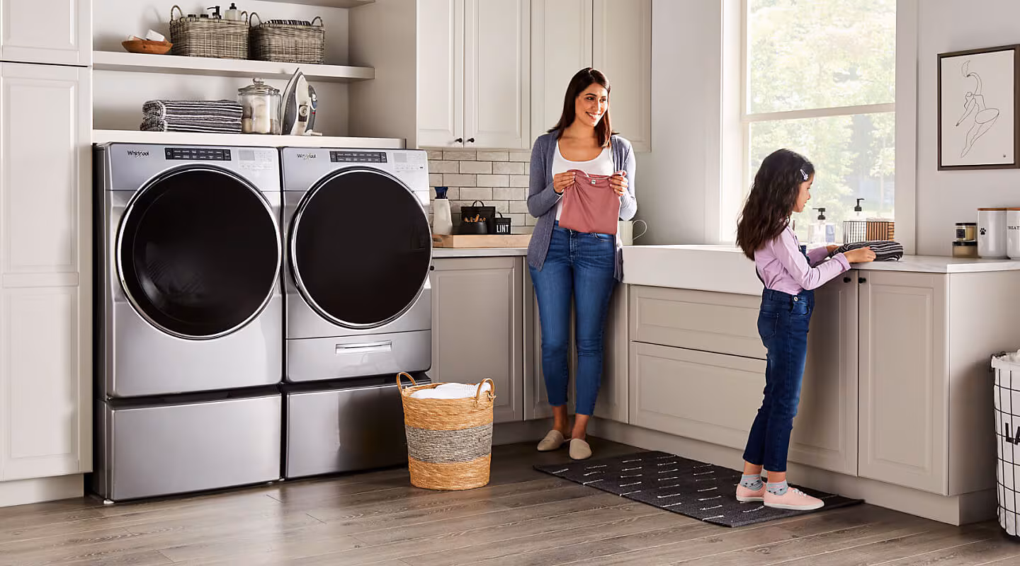 Woman and daughter doing laundry together in a home laundry room