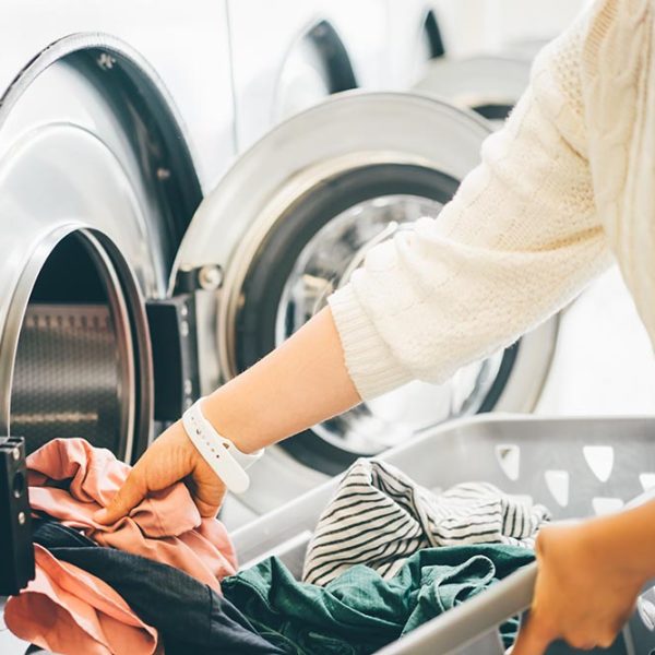 Woman placing laundry into a basket in a commercial laundry room