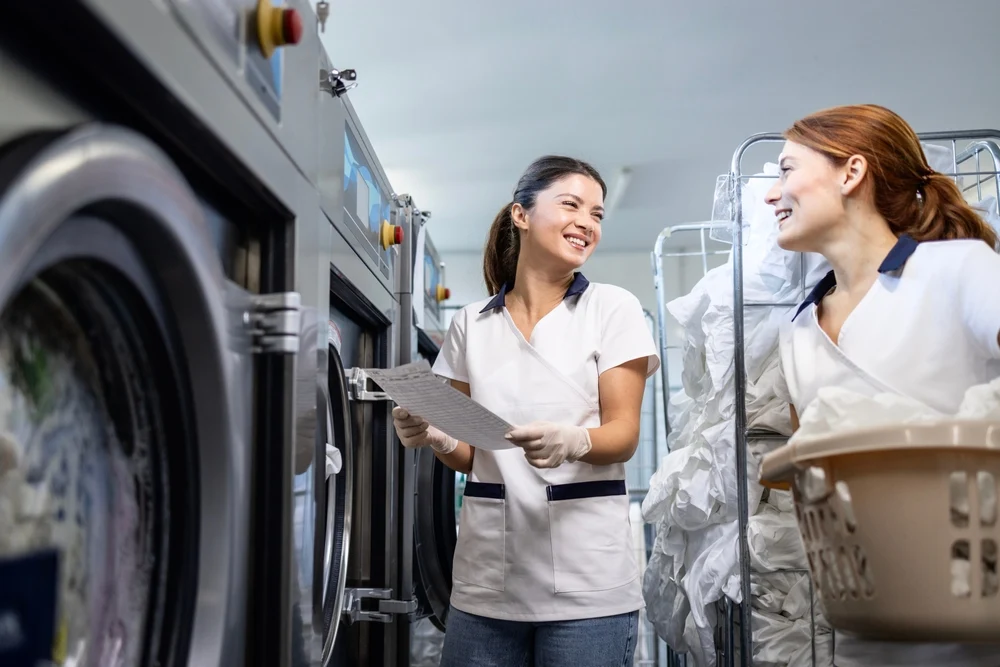 Two women sorting freshly laundered clothes in a laundry room
